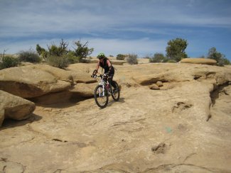 Linda qui n&eacute;gocie une descente de slickrock dans Salt Wash Trail